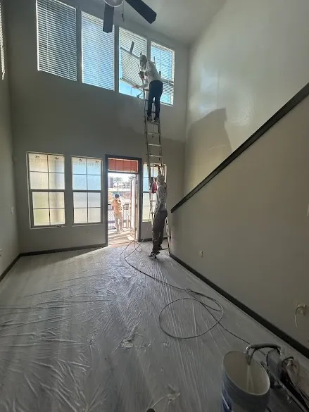 JAE Painting crew spray painting a two-story living room in Phoenix with floors fully masked